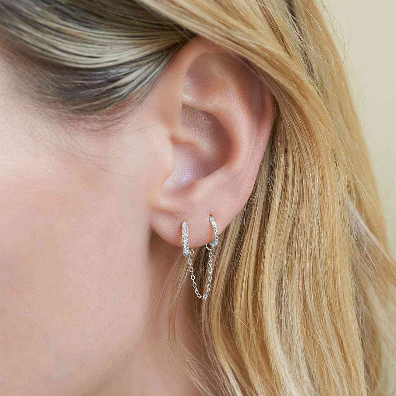 14K white gold chain earring jacket linking a clear-stone huggie and stud, shown on a model's lobe