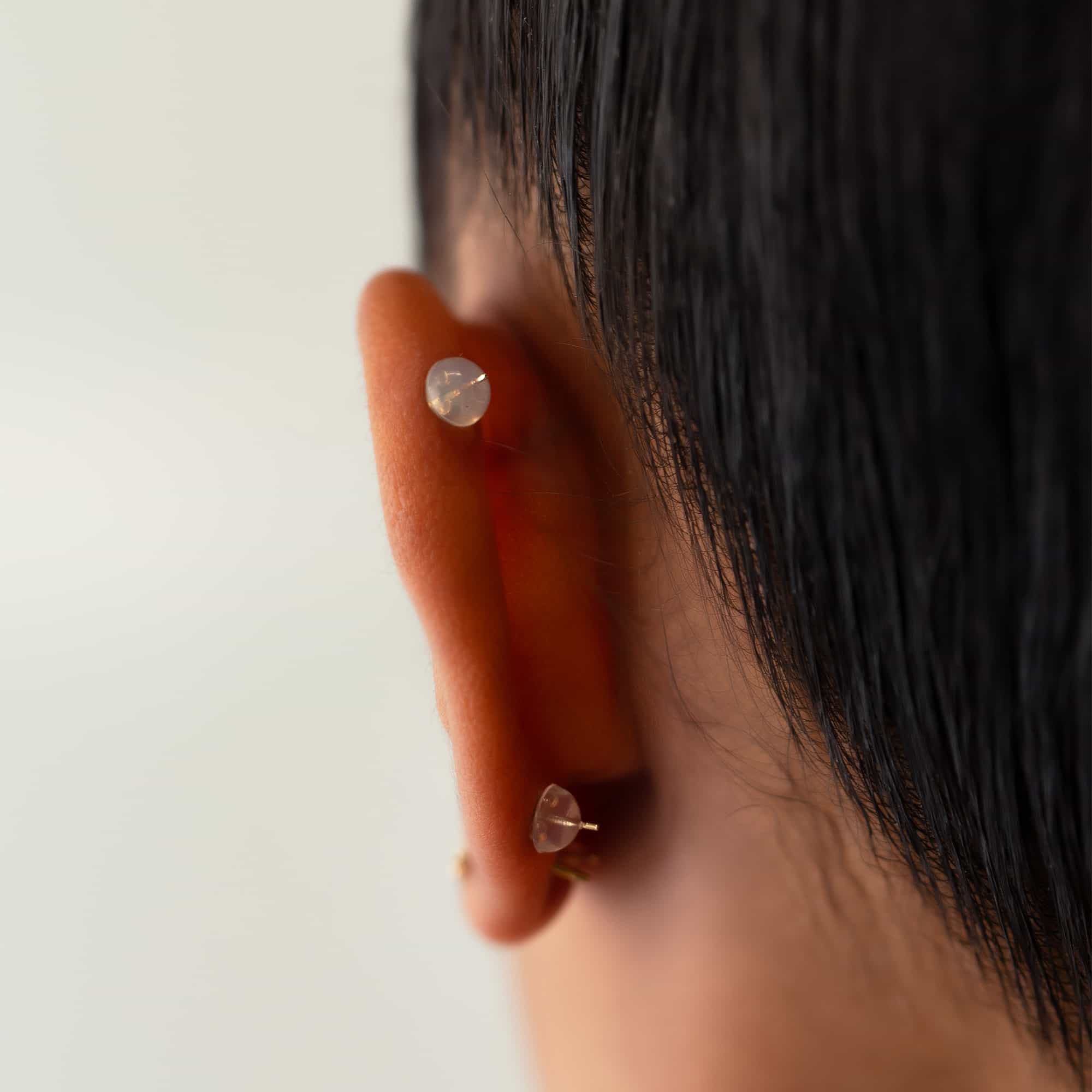 Clear silicone earring back with a 14K gold core securing a stud, shown on a model's lobe