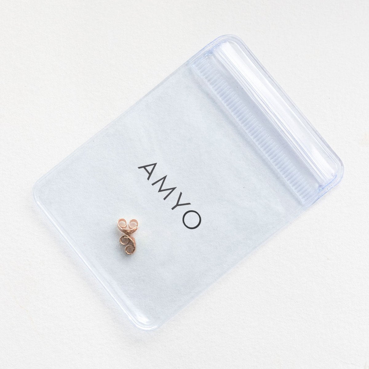 14K rose gold earring backs on a frosted AMYO pouch, close-up of friction butterfly backs
