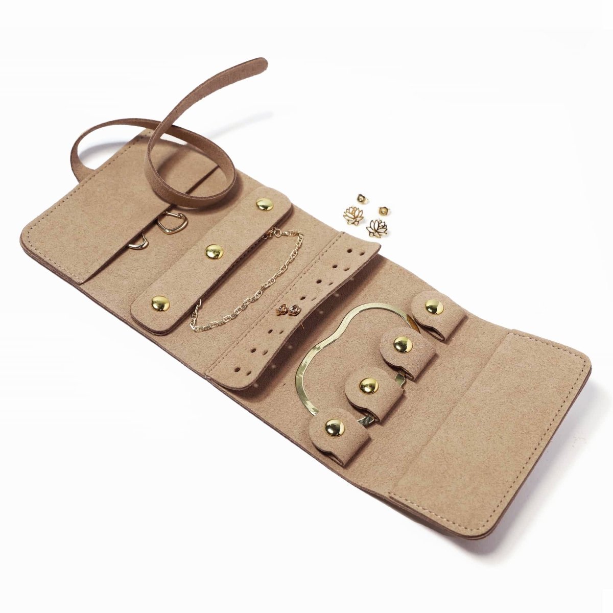 Tan suede travel jewelry roll opened flat with snap compartments holding gold jewelry, on a white background