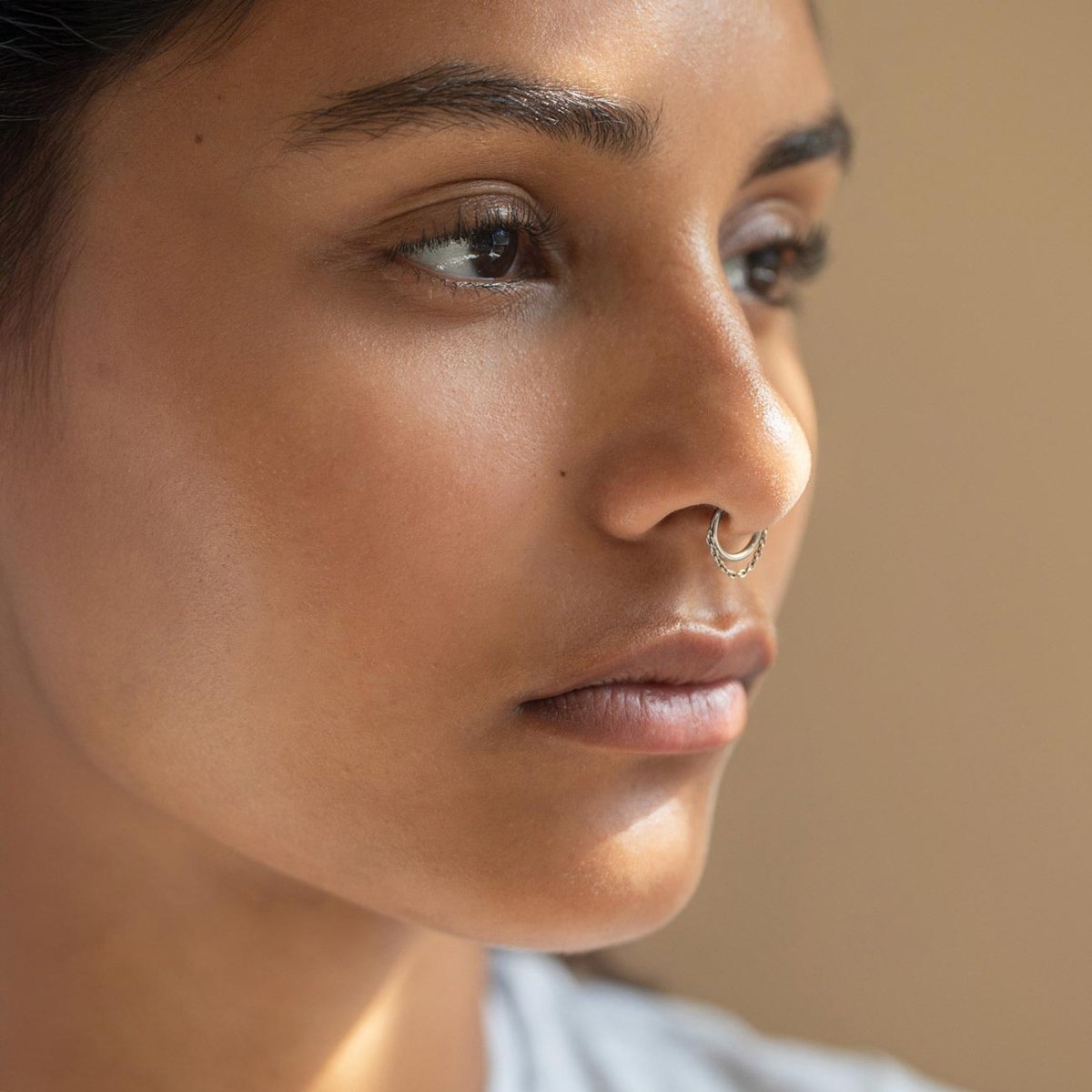 Titanium seamless clicker nose hoop with a chain detail, shown on a model's nose