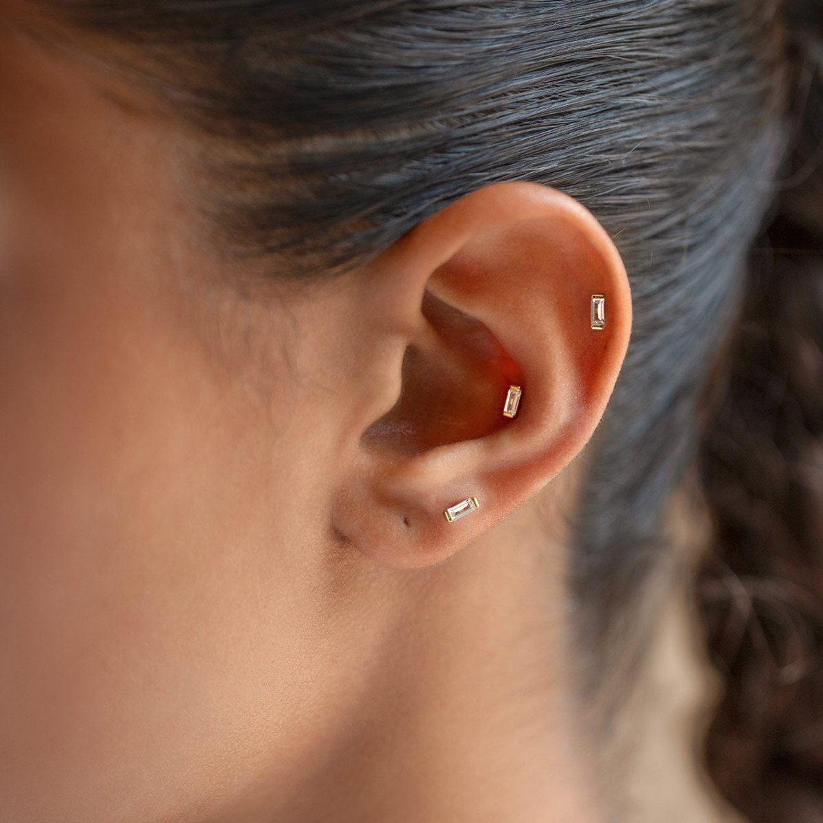 Gold Vermeil flat back stud earrings with baguette-shaped crystals, shown on a model's ear.