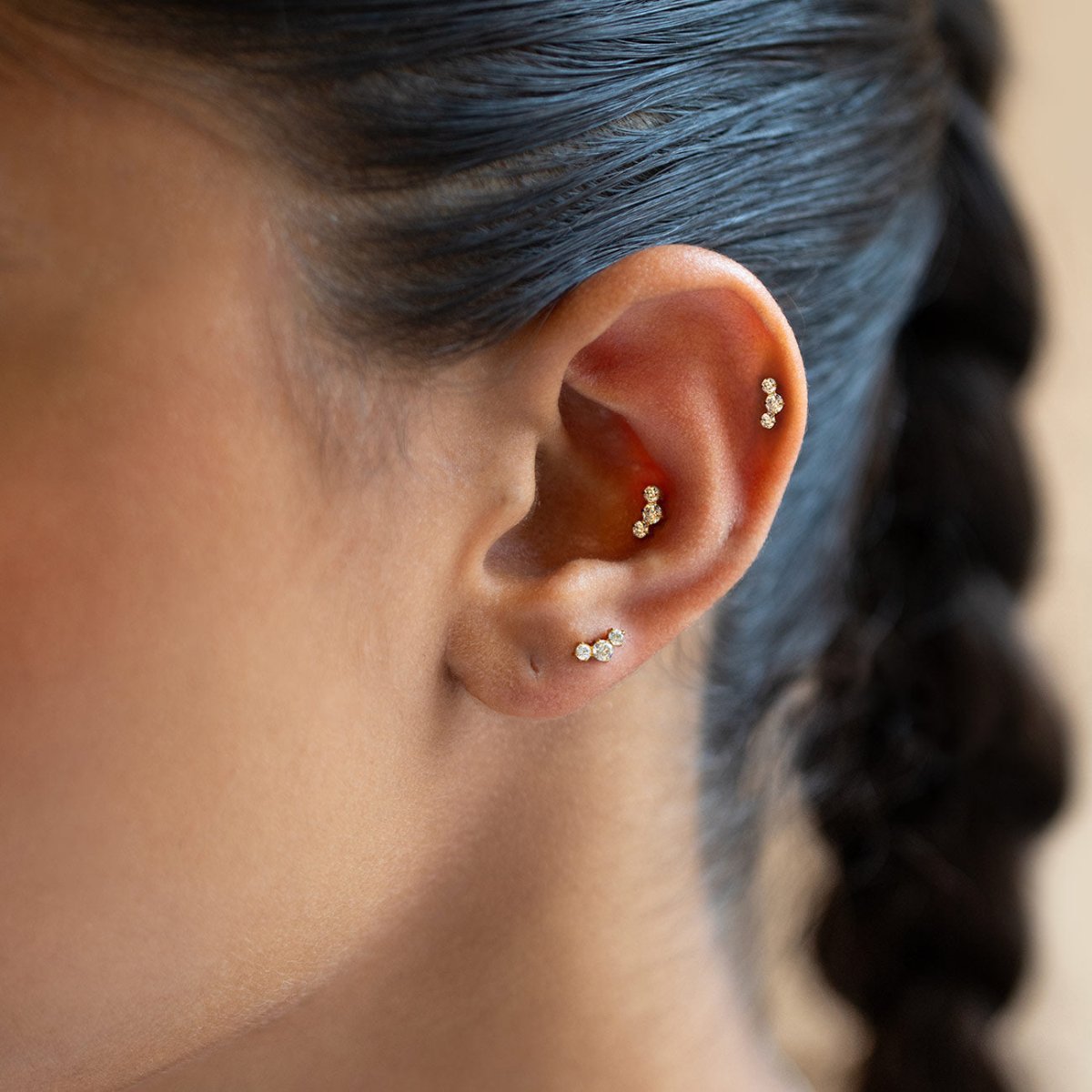 Gold Titanium pavé flat back stud earrings with three round crystals, shown on a model's ear.