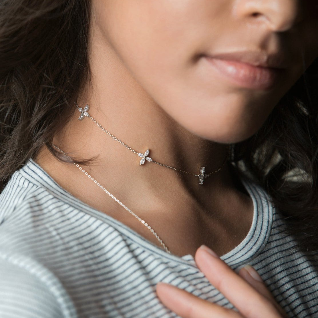 Sterling silver clear crystal flower choker shown on a model's neckline, layered with a finer chain