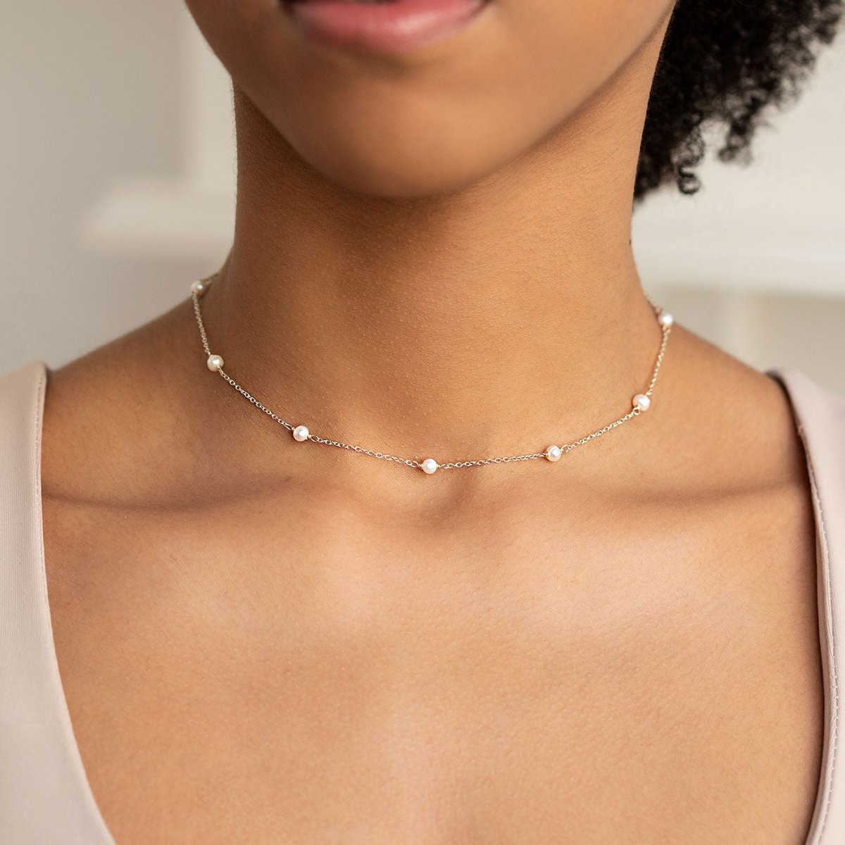 Sterling silver pearl station chain choker with small white pearls, shown on a model's neckline