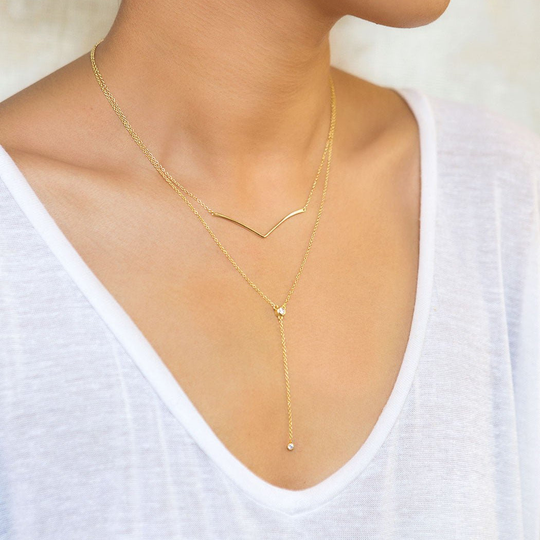 Gold vermeil chevron bar necklace layered with a lariat chain, shown on a model's neckline