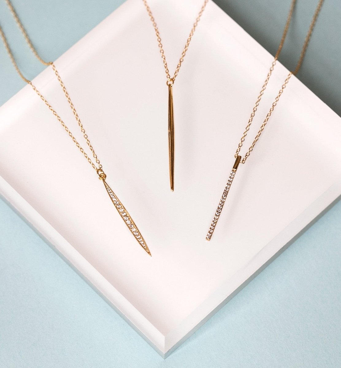 Gold vermeil pavé and polished spike pendant necklaces styled on a white tray