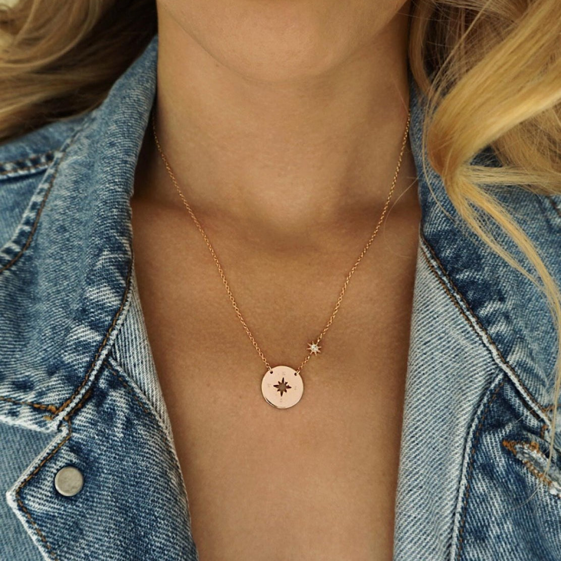 Rose gold vermeil compass disc necklace with a star station, shown on a model's neckline