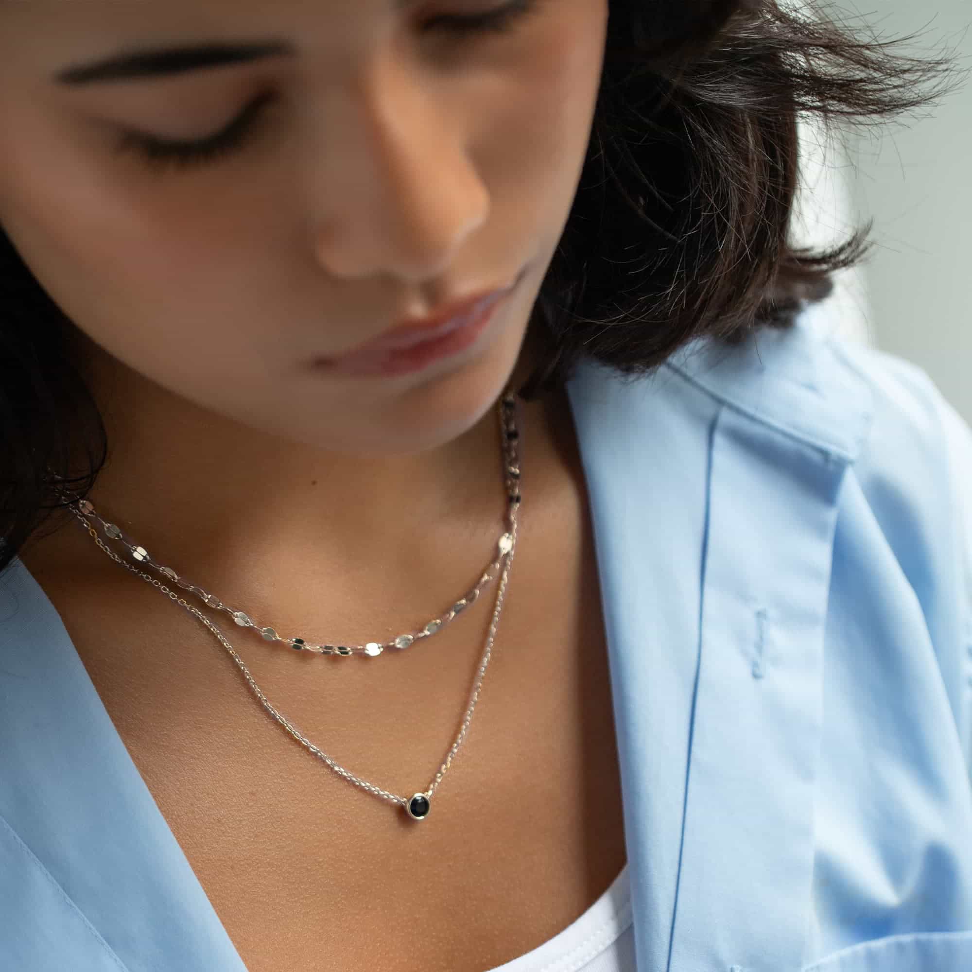 Sterling silver blue sapphire solitaire necklace shown layered on a model's neckline
