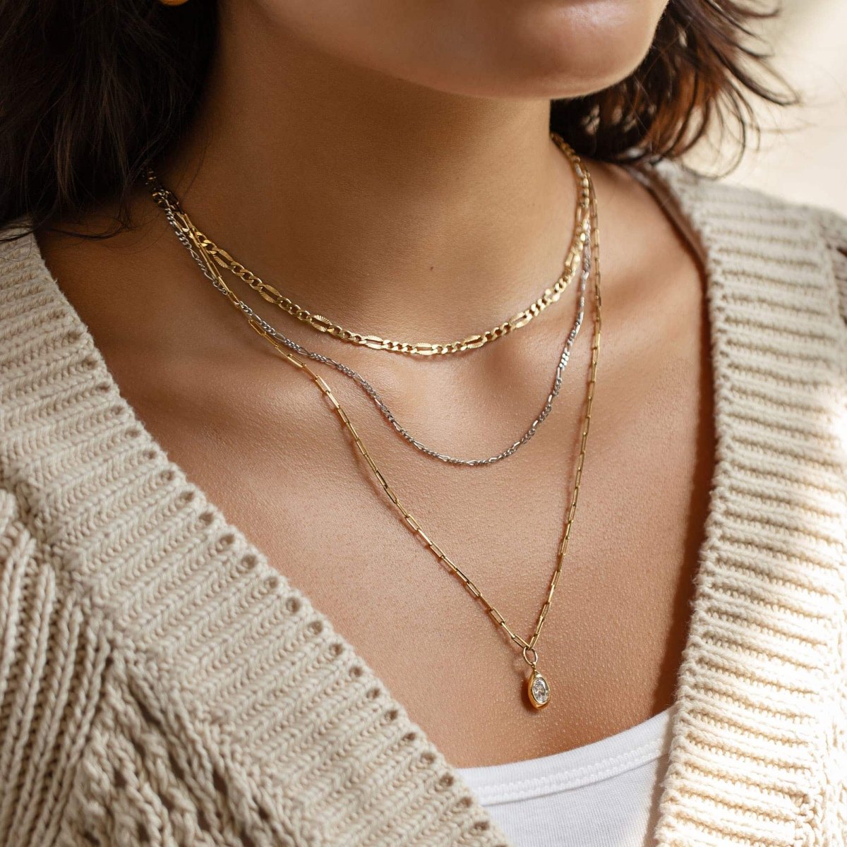 Sterling silver Figaro chain necklace layered with two delicate chains, shown on a model's neckline