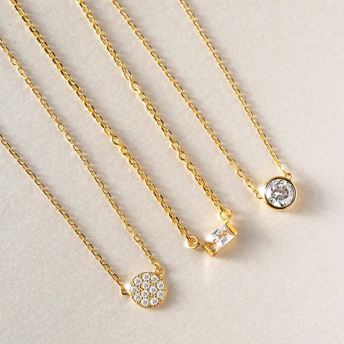 Gold vermeil baguette necklace pendant with white zirconia, close-up detail on a light surface