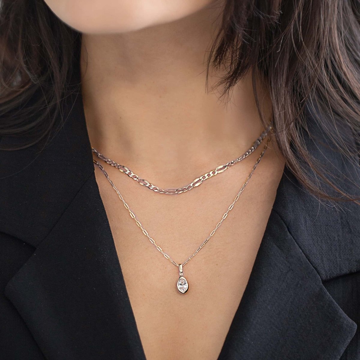 Silver layered chain necklaces with a marquise clear-stone pendant, shown on a model's neckline