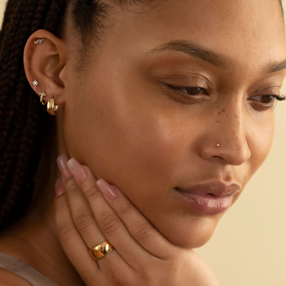 14K gold ball nose stud worn on a model's nostril, profile view