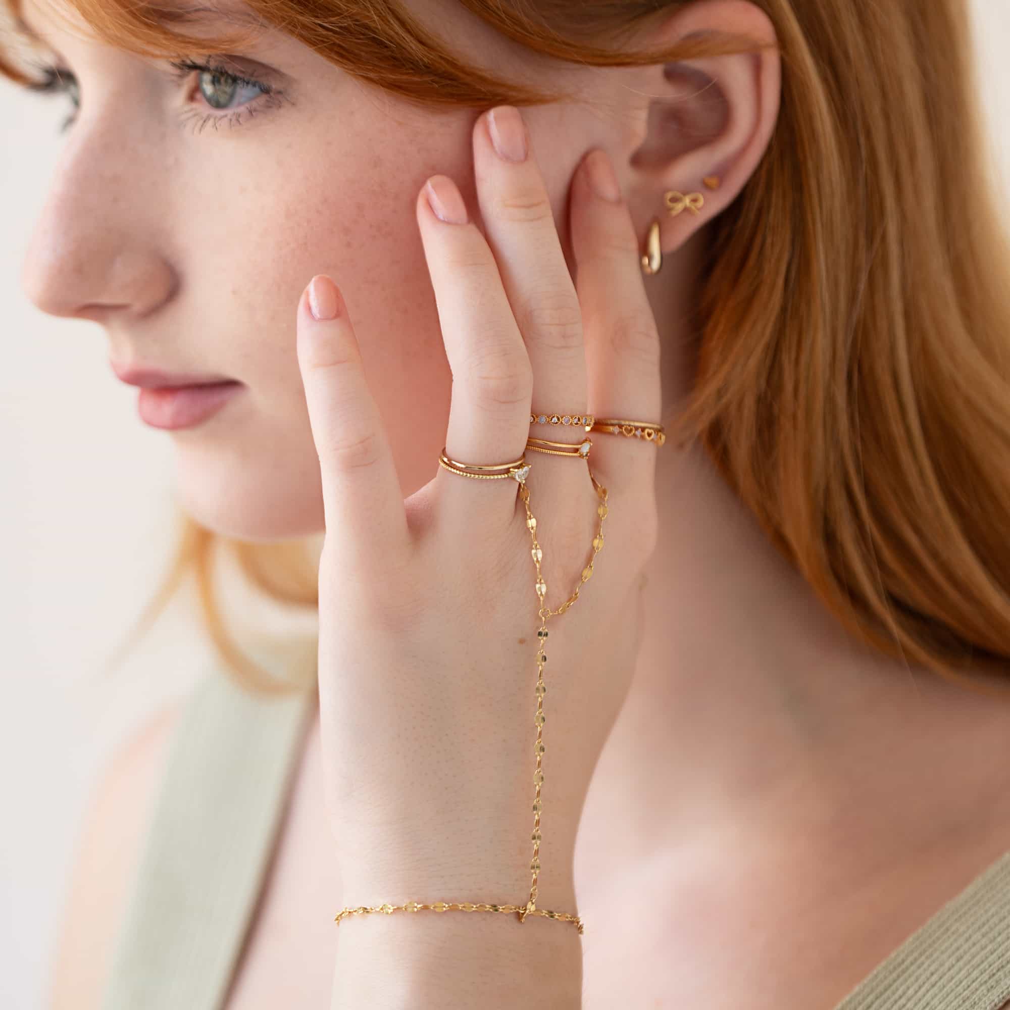 Gold vermeil faceted hand chain linking a ring to a bracelet, shown on a model's hand