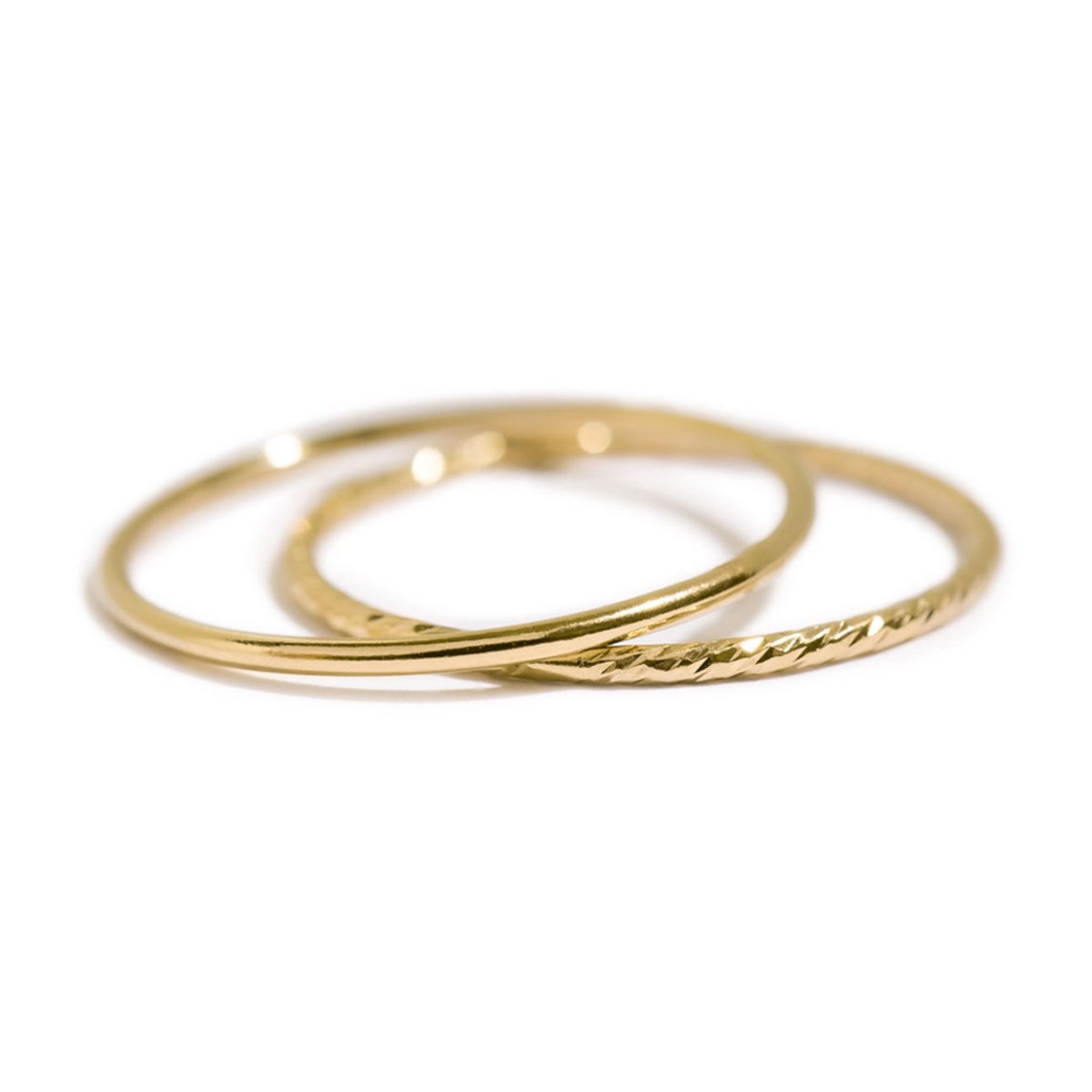 Gold-filled stacking rings, a smooth band and a faceted textured band, shown loose on a white background