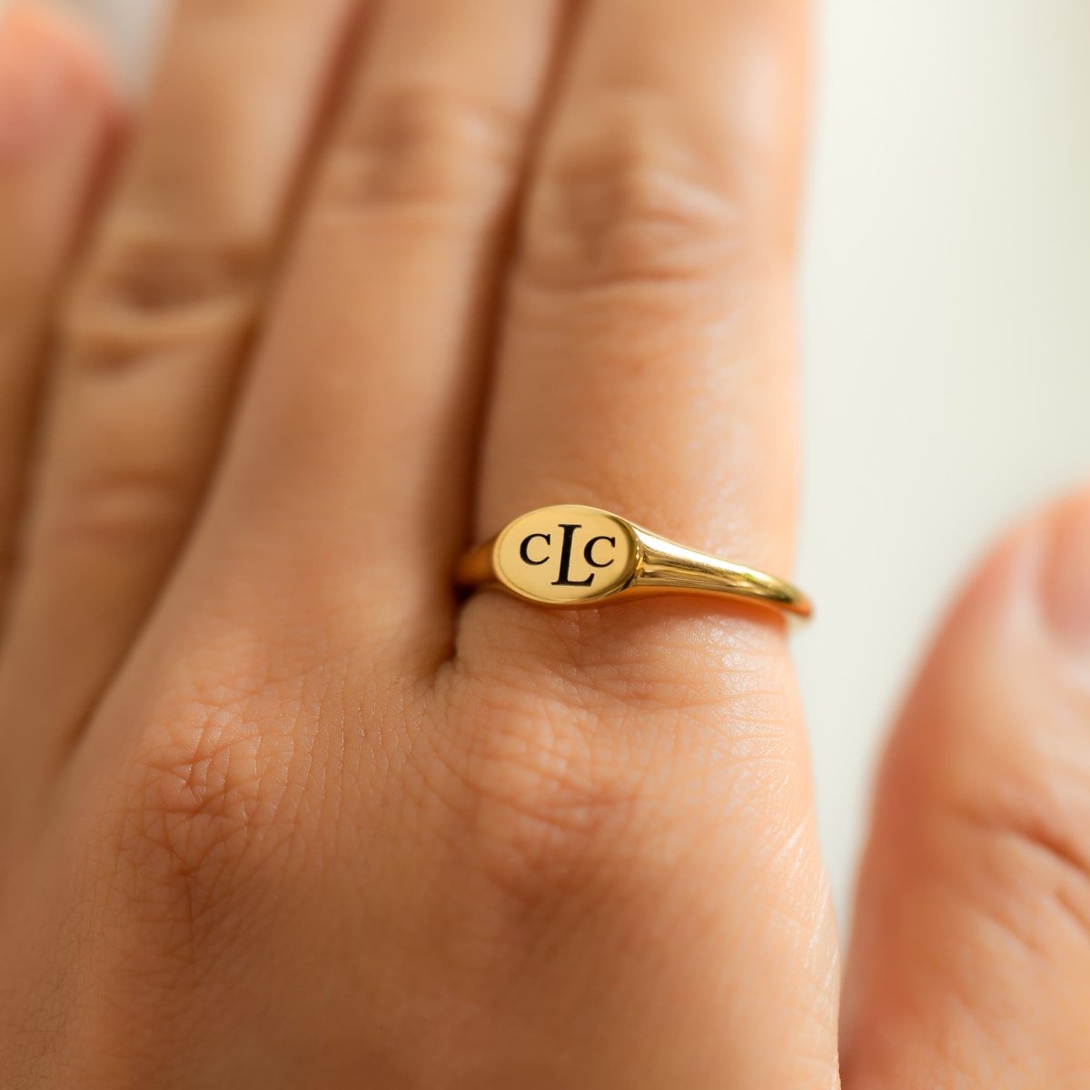 Gold vermeil oval signet ring engraved with a monogram, shown on a model's finger