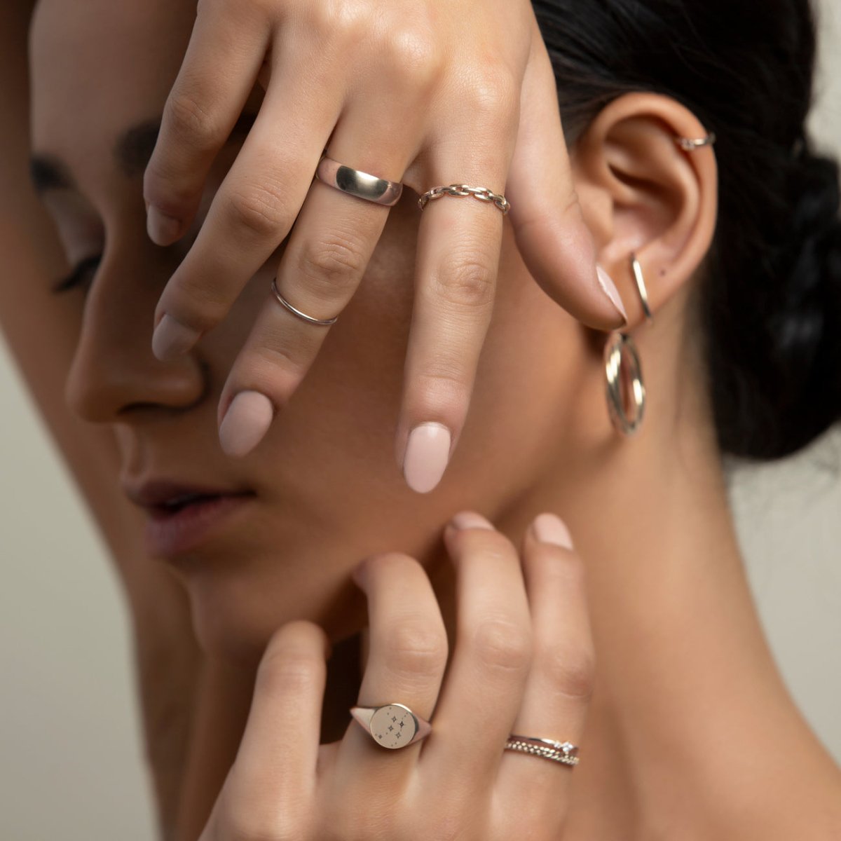 Sterling silver thick domed band ring worn on a hand among stacked rings and hoops