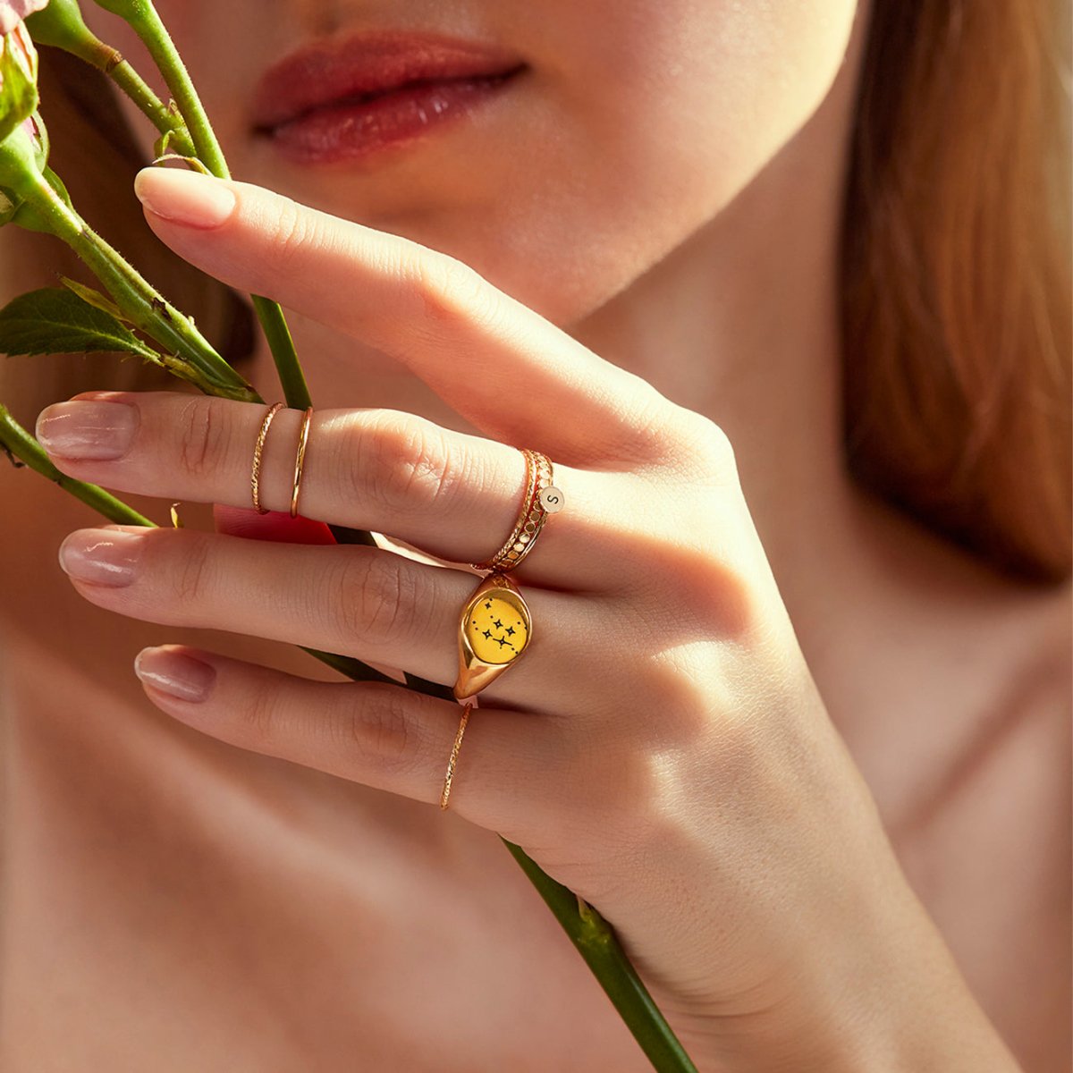 Gold-filled flat beaded band ring stacked with a star signet ring, shown on a model's hand