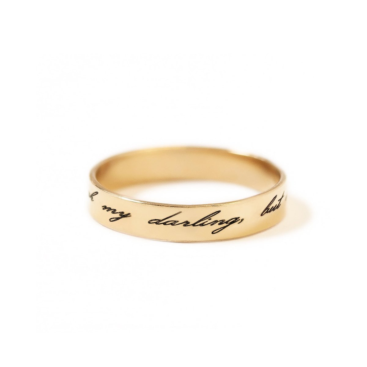 Gold-filled band ring engraved with a script message, on a white background