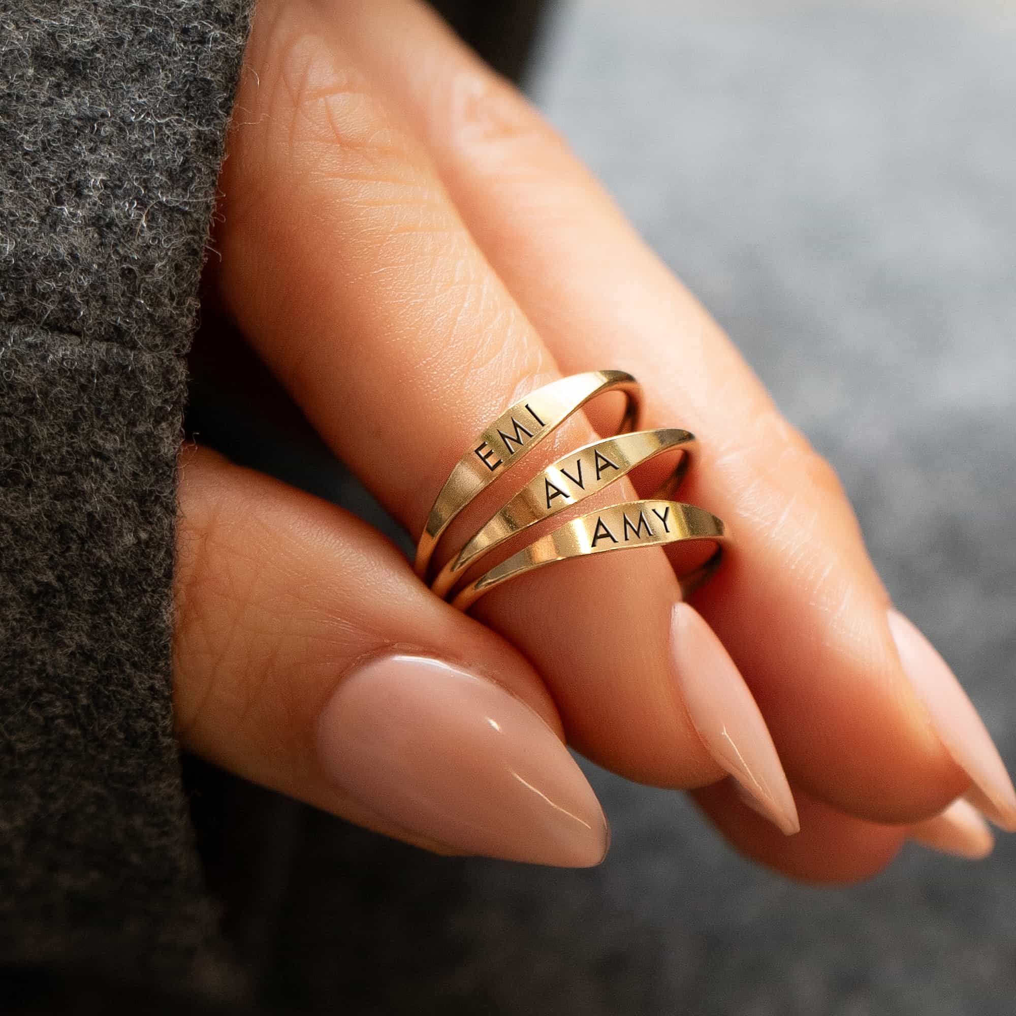 Gold-filled thin signet rings engraved with names, stacked on a model's fingers