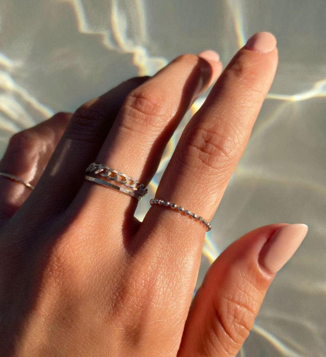Sterling silver curb chain ring shown beside a beaded ring on a model's fingers