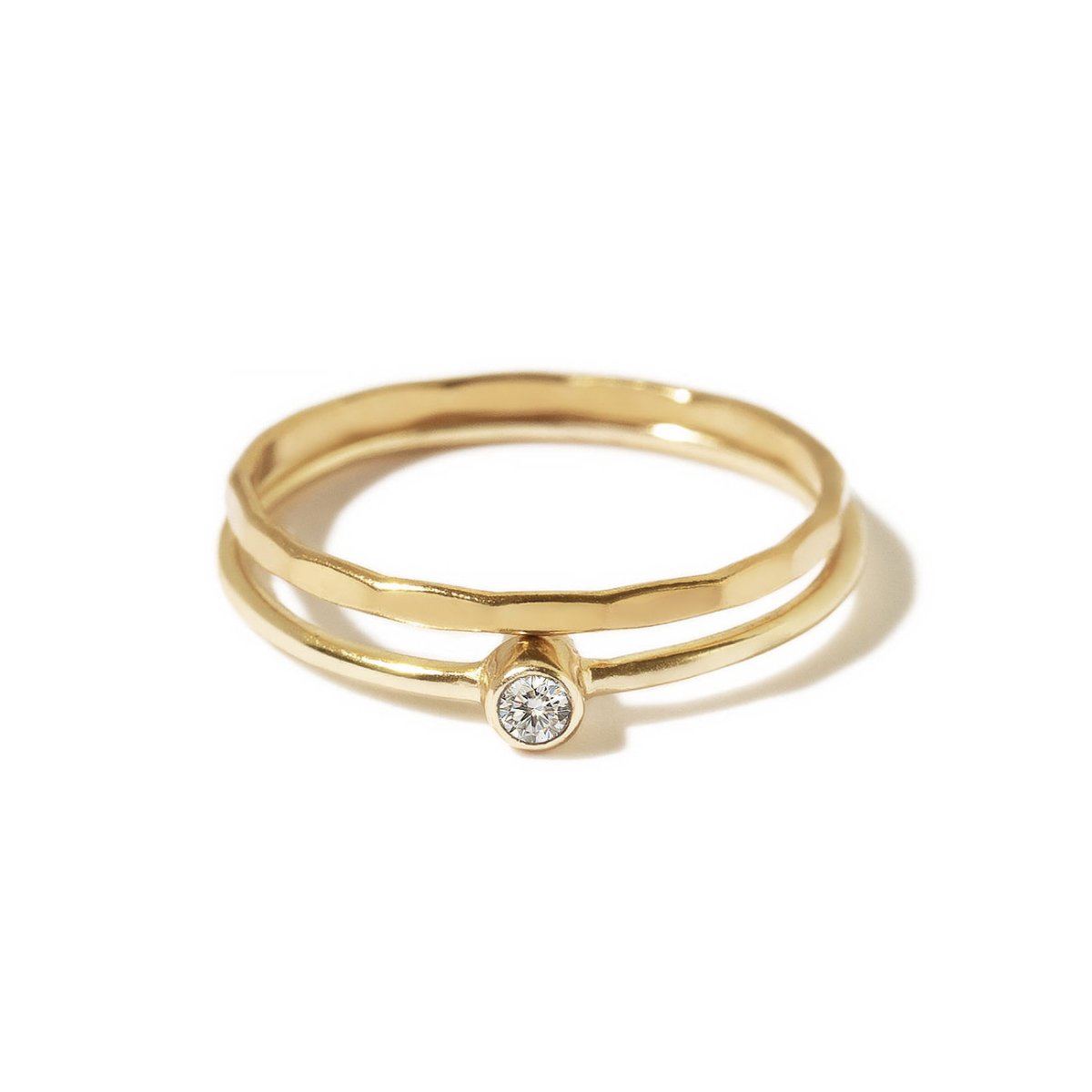 Gold-filled solitaire and hammered ring set with a clear bezel-set stone, on a white background