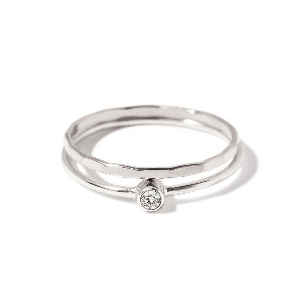 Sterling silver solitaire and hammered ring set with a clear bezel-set stone, on a white background