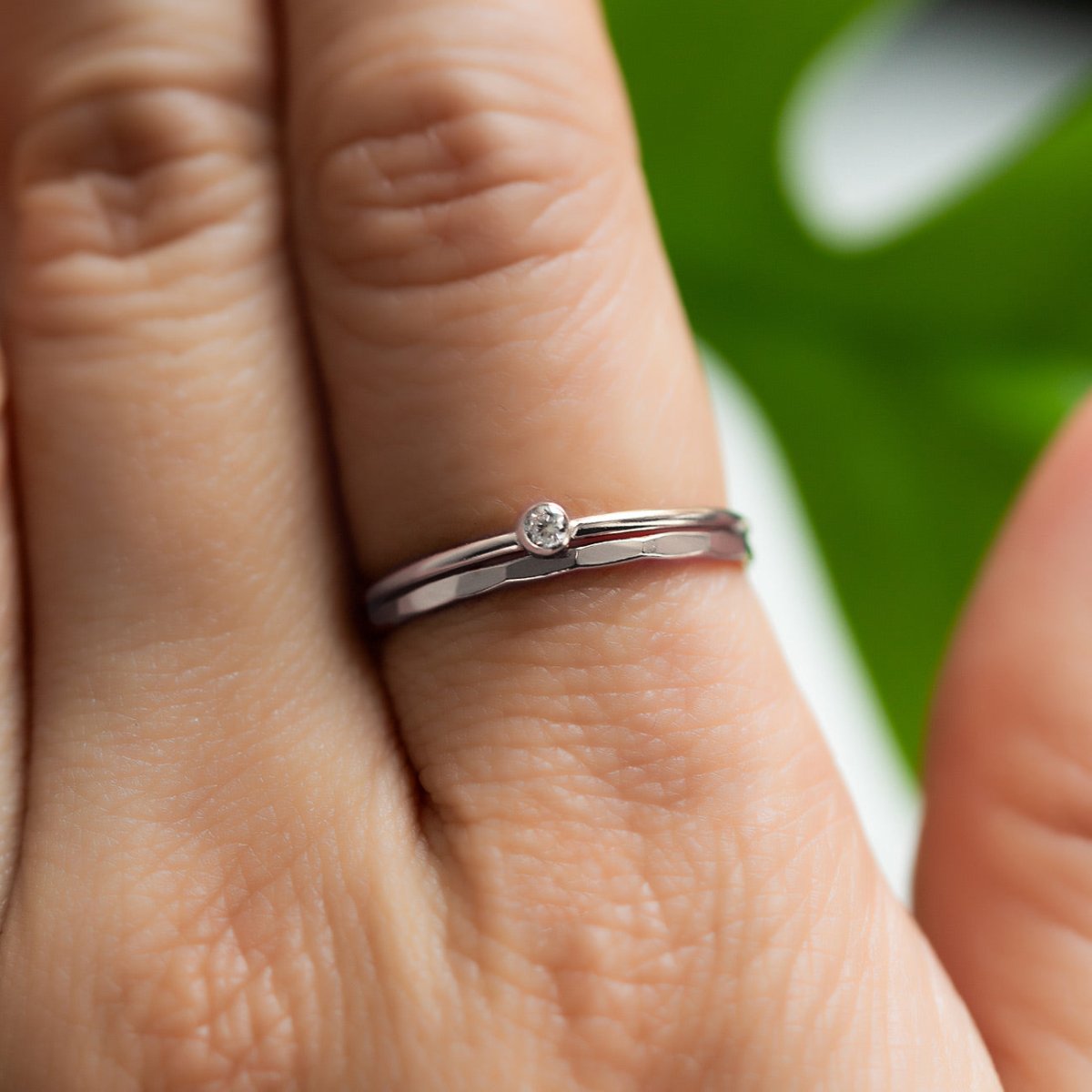 Sterling silver hammered band with a clear bezel-set stone, close-up detail on a model's finger