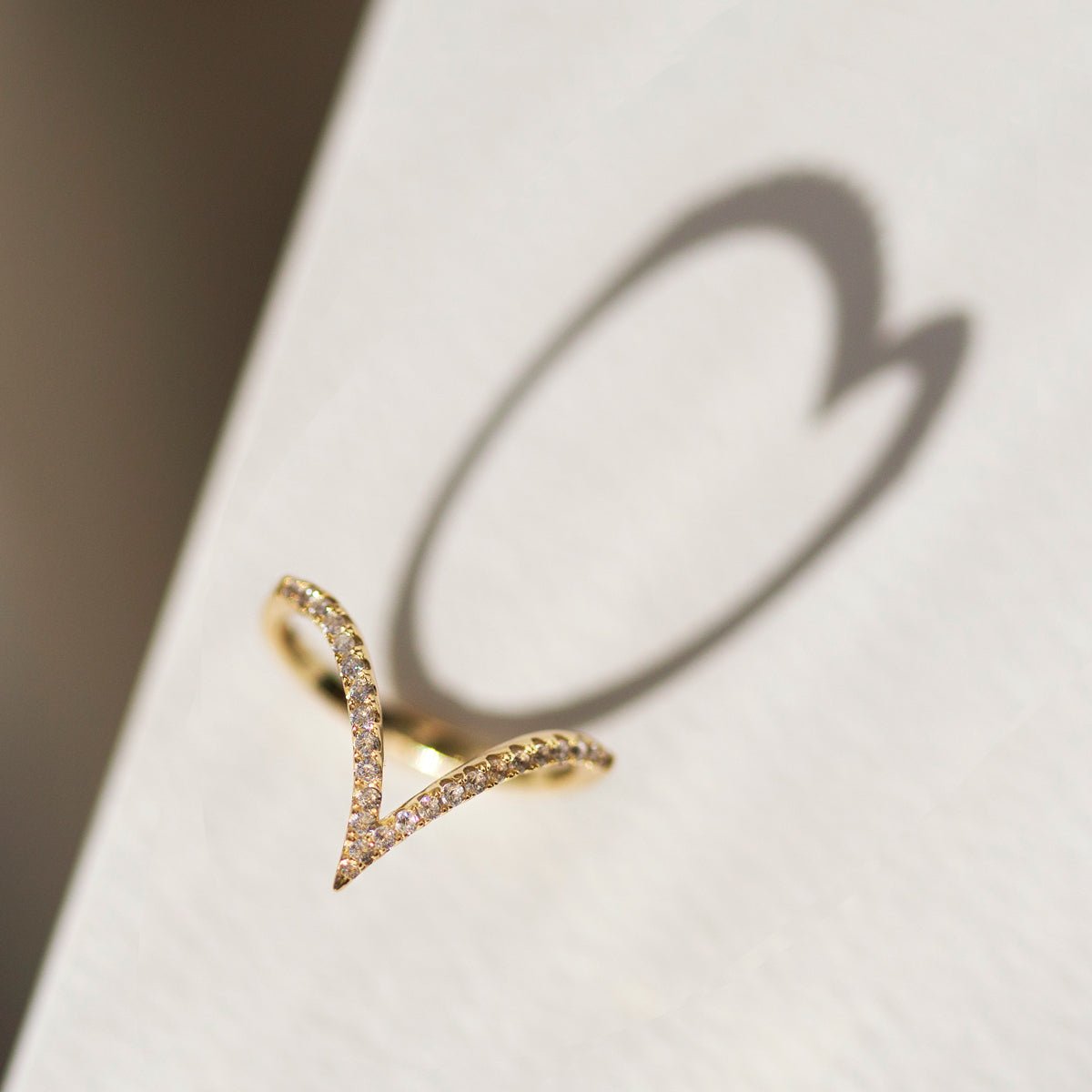 Gold vermeil pavé chevron ring with clear crystals along a V-shaped band, close-up detail