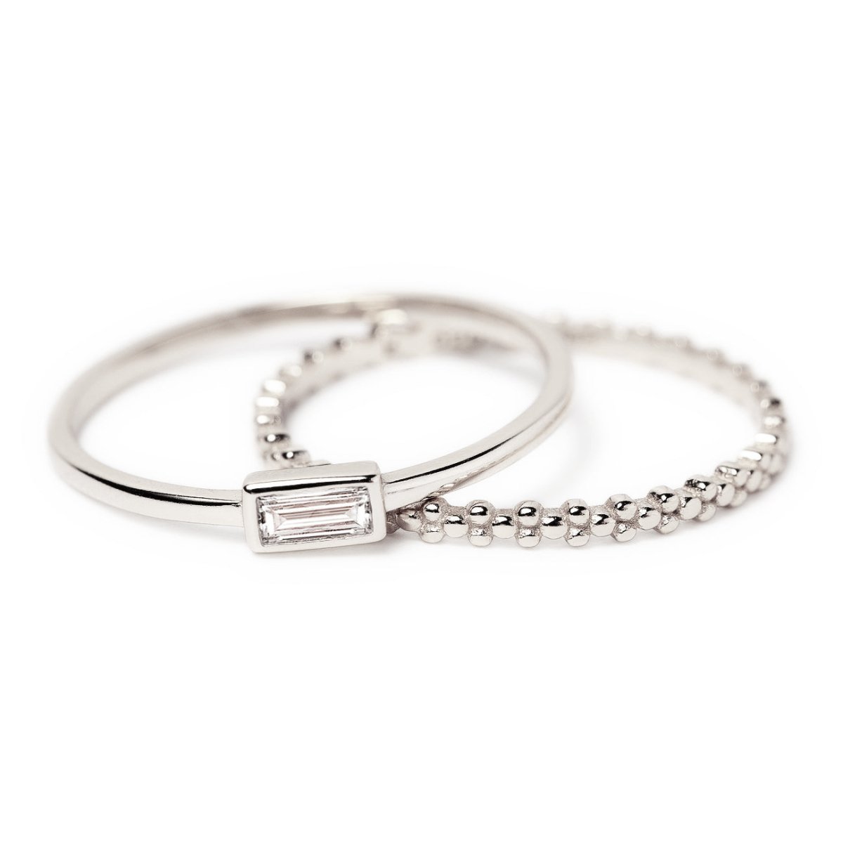 Sterling silver ring set, a baguette white zirconia ring and a beaded eternity band, on a white background
