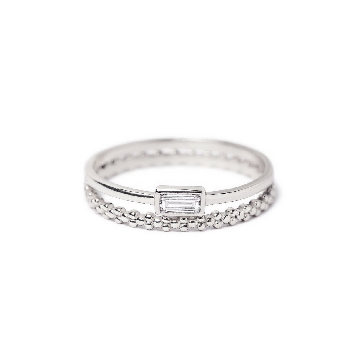 Sterling silver ring set with a baguette white zirconia and a beaded eternity band, on a white background