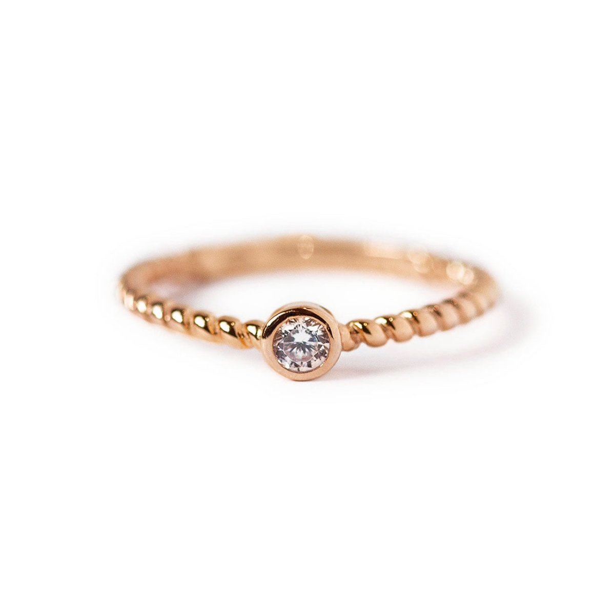 Rose gold vermeil solitaire rope ring with a round clear stone, on a white background