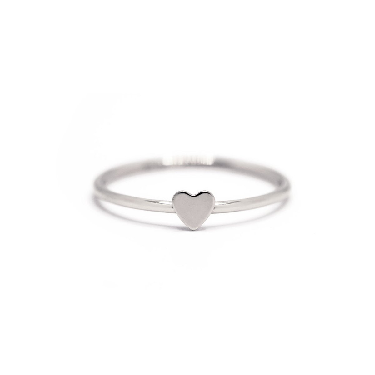 Sterling silver tiny heart ring with a thin band and flat heart top, on a white background