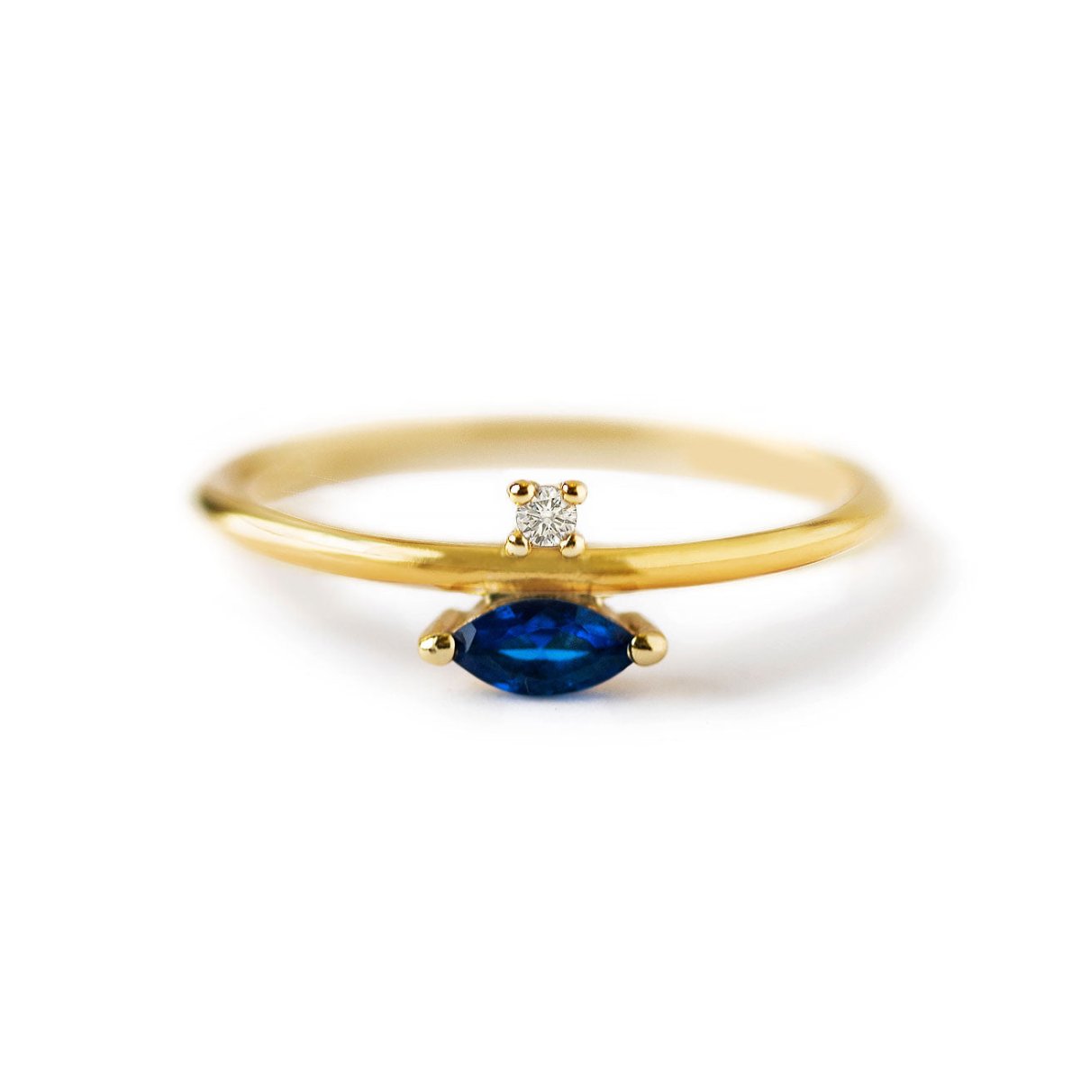 Gold vermeil ring with a blue sapphire marquise stone and a small clear accent stone, on a white background