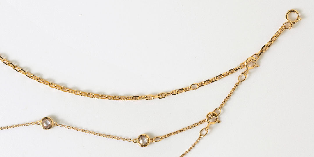 Close-up of gold chain necklaces with crystal accents and spring-ring clasps