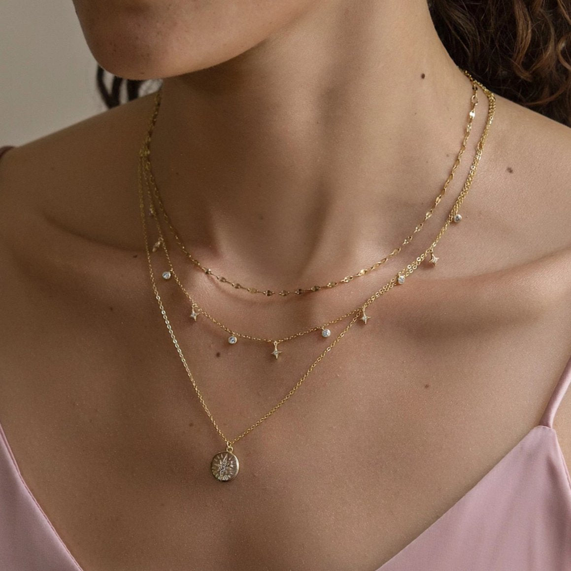 Gold vermeil star and zirconia dangle layered necklaces shown on a model's neckline