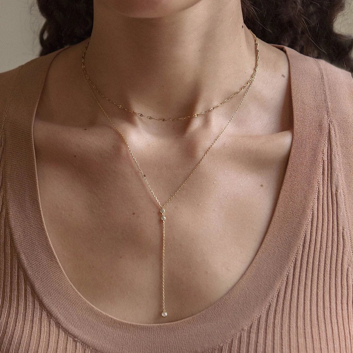 Gold vermeil layered lariat duo with a dangling clear stone drop, shown on a model's neckline