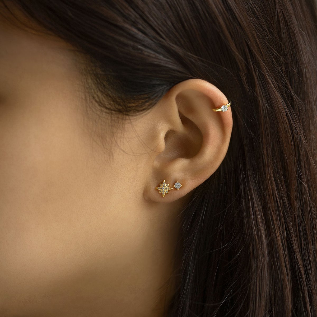 Gold vermeil starburst pavé stud with white zirconia, shown on a model's lobe with a gold ear cuff