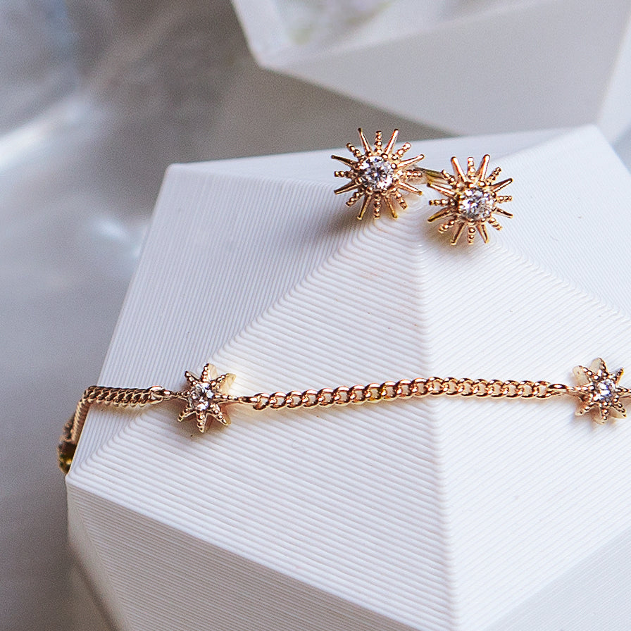 Rose gold vermeil pavé star studs and a star station chain bracelet, on a white prop