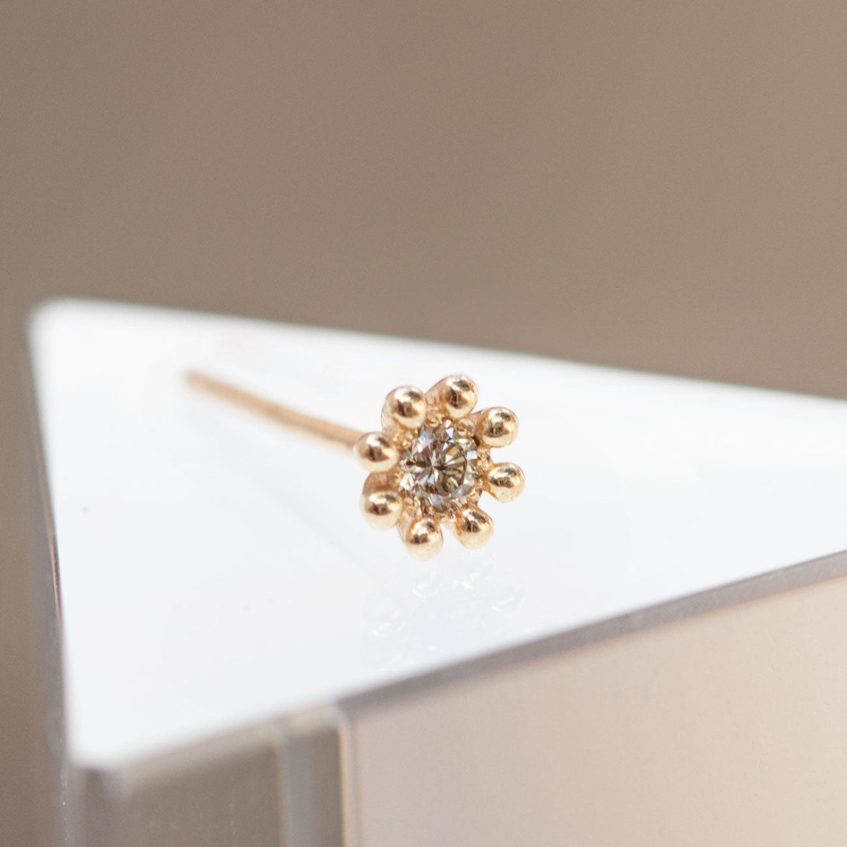 14K gold beaded flower stud with a round diamond center, shown on a pale surface