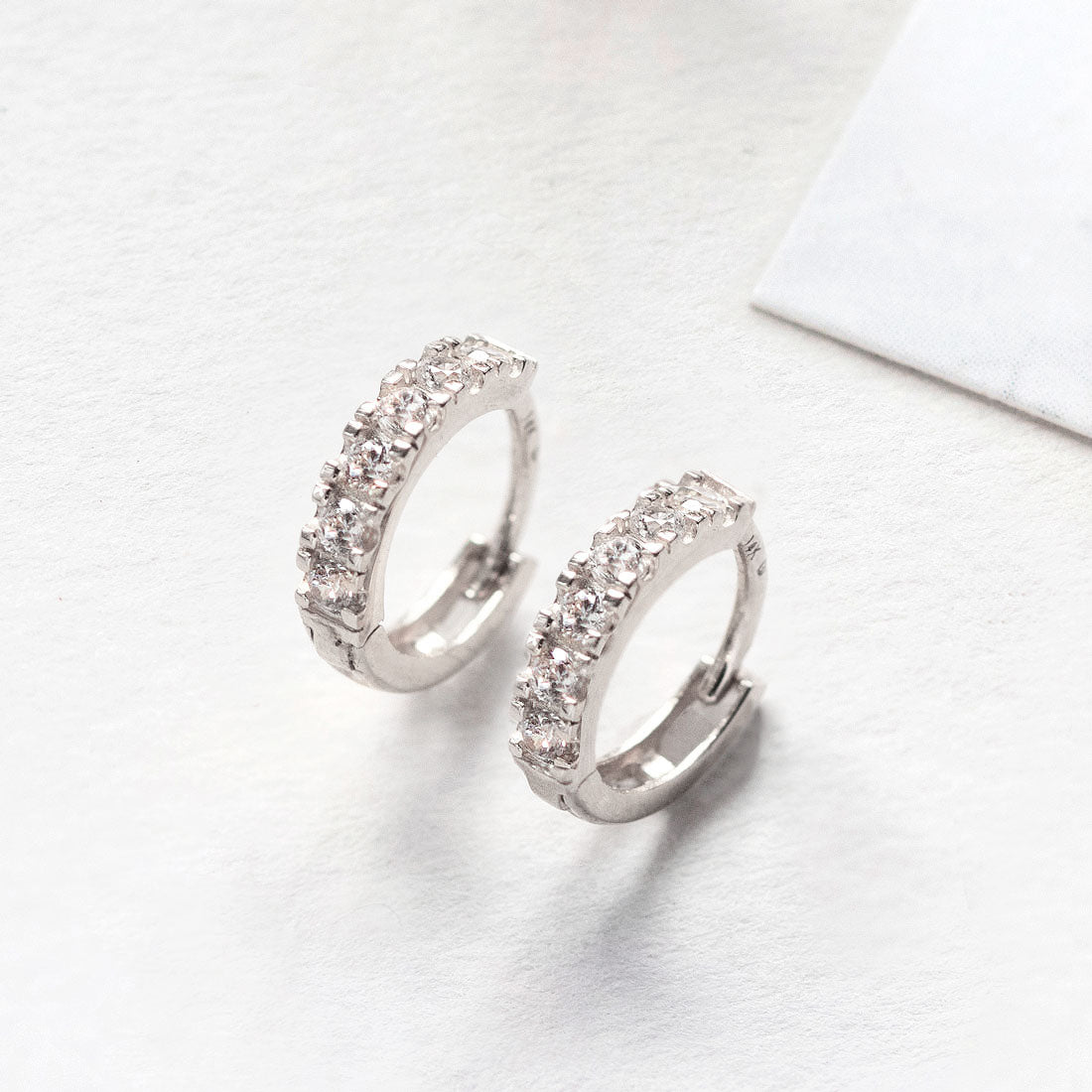 Close-up of 14k white gold pave huggie earring