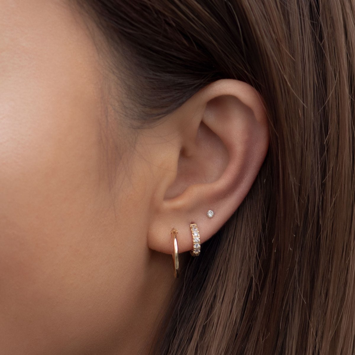 14K gold diamond pave huggie hoop and thin plain hoop shown on a model's ear