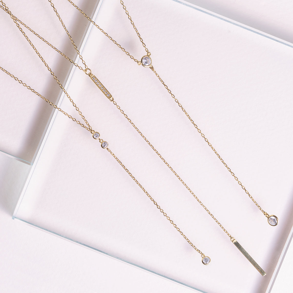 Layered silver bezel and lariat bar necklaces shown on a model's neckline