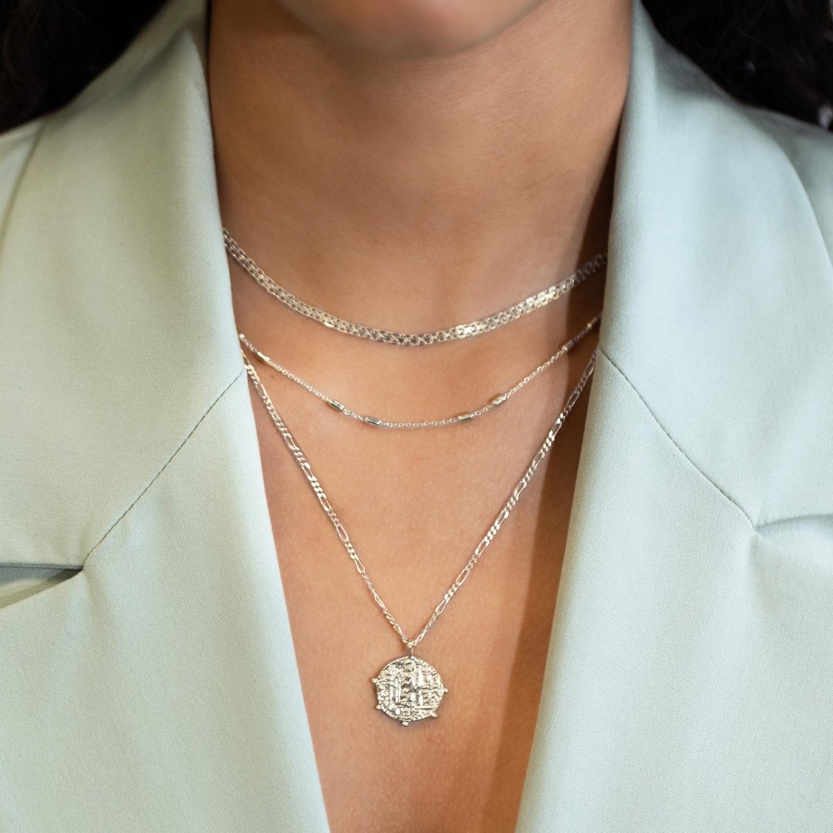 Sterling silver Grecian coin pendant layered with two chains, shown on a model's neckline