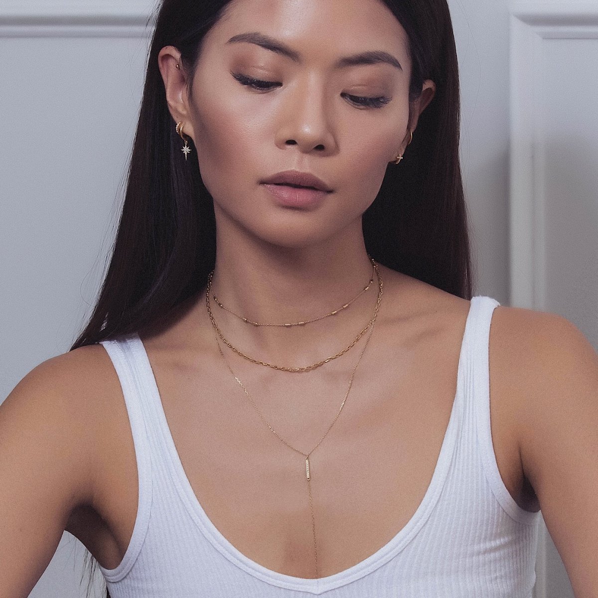 Gold vermeil layered lariat necklace with a pavé bar drop shown on a model in a white tank