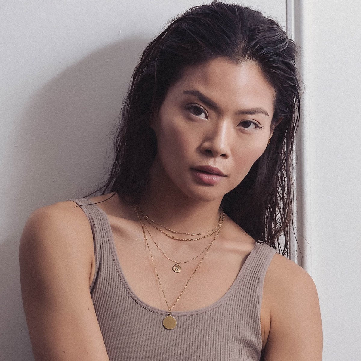Gold vermeil round disc pendant necklace layered with chains, shown on a model's neckline