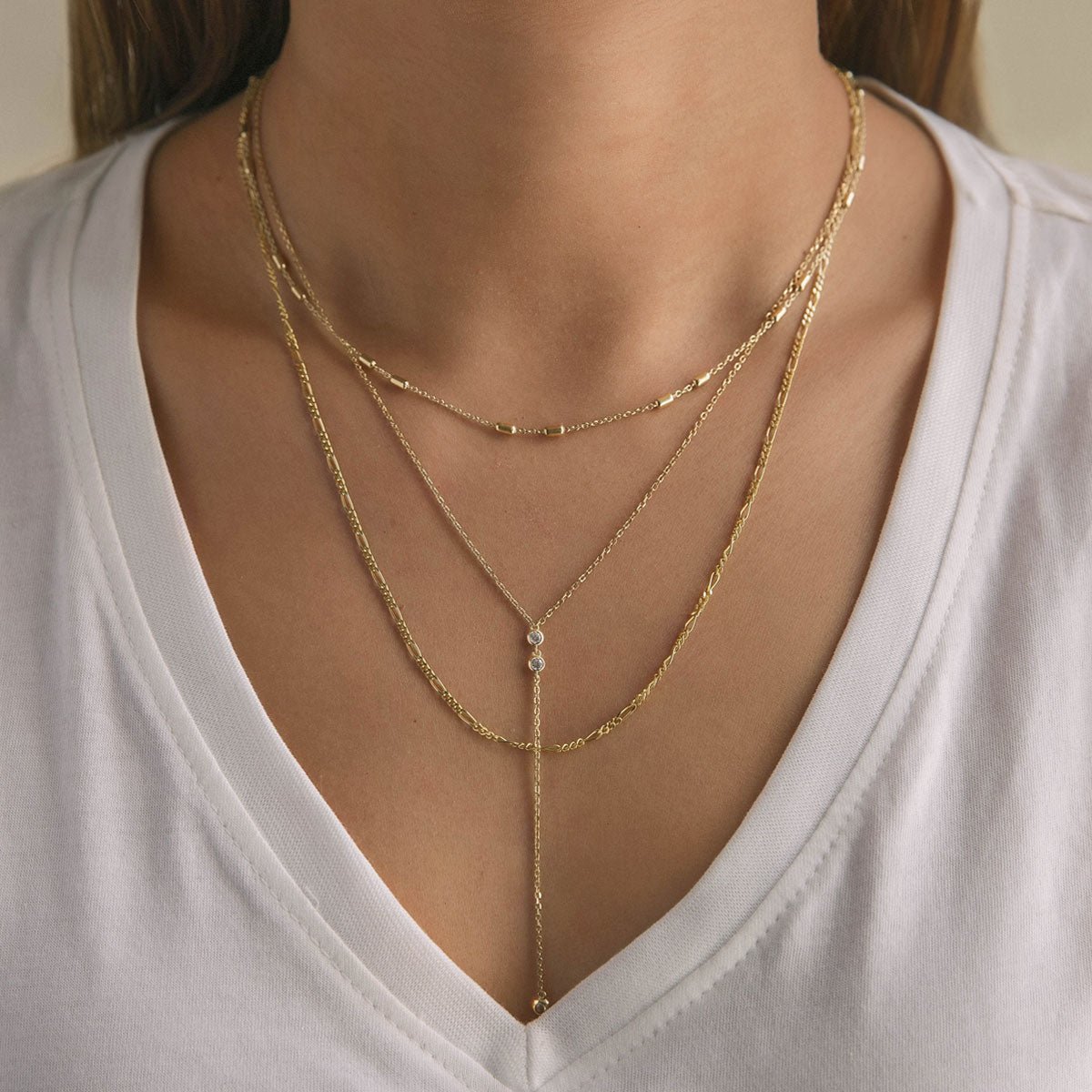 Gold vermeil layered necklace set with a Y-drop lariat of clear stones, shown on a model's neckline