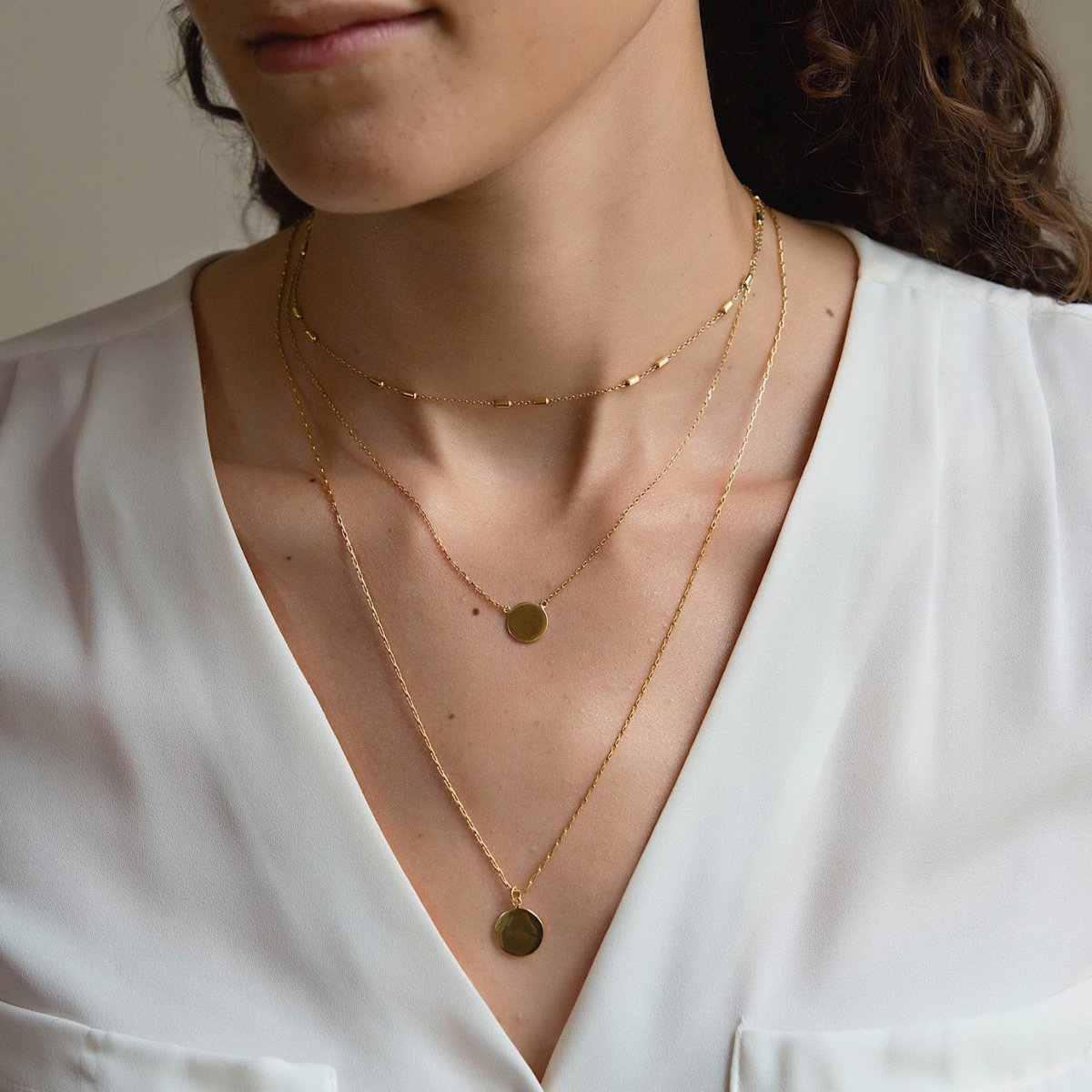 Gold vermeil layered choker and two disc pendant necklaces, shown on a model's neckline