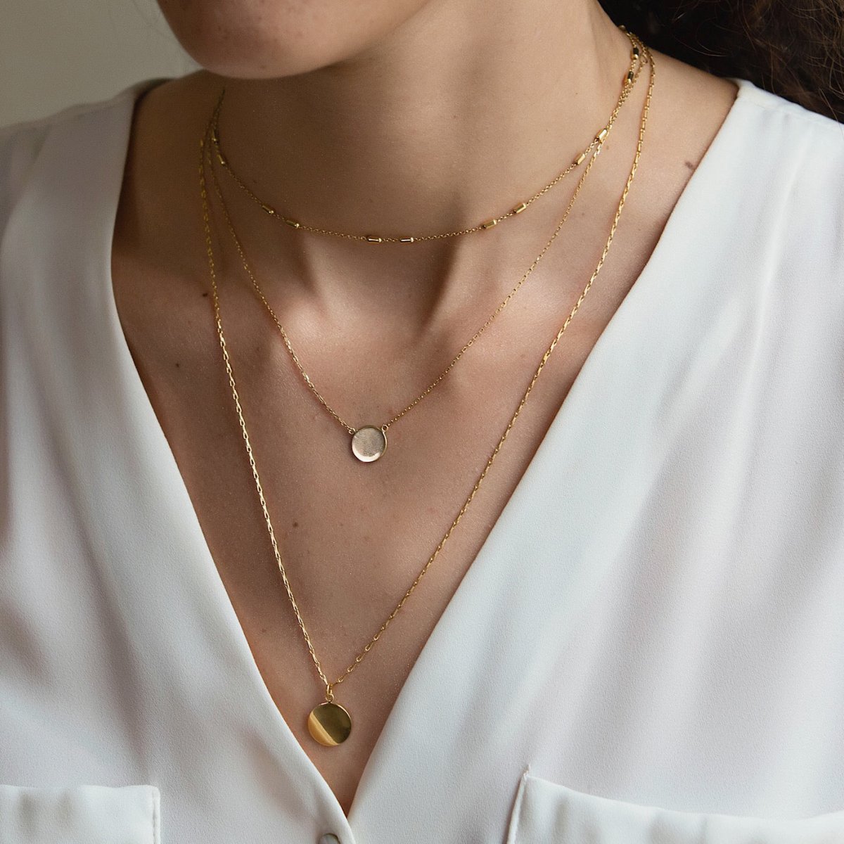 Gold vermeil round disc pendant necklace shown layered on a model's neckline over a white top