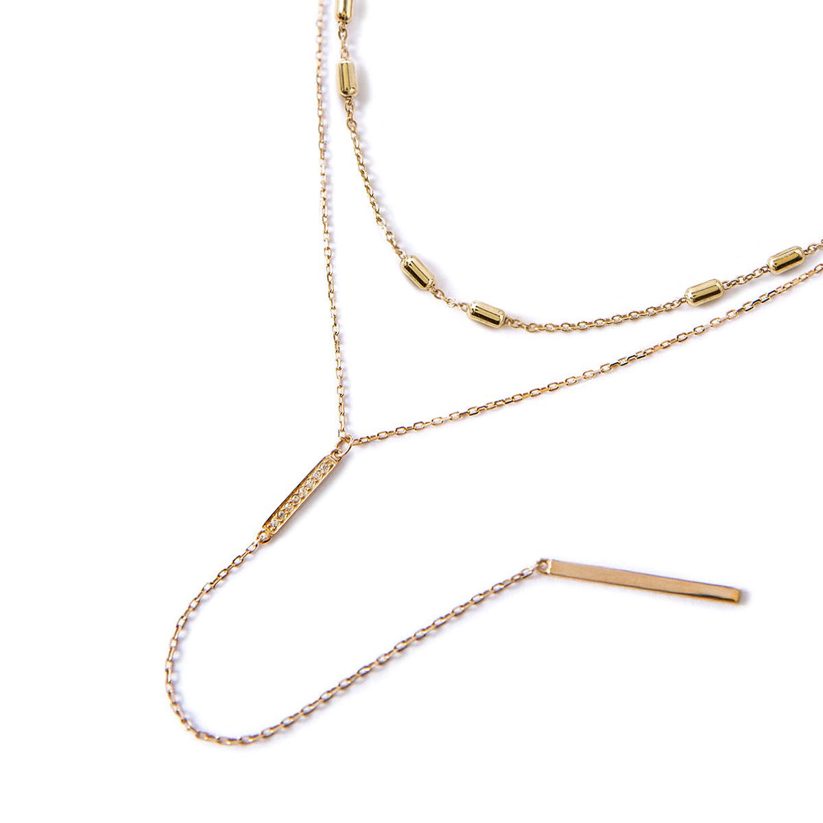 Gold vermeil choker and lariat duo with a pave bar set with clear stones, on a white background